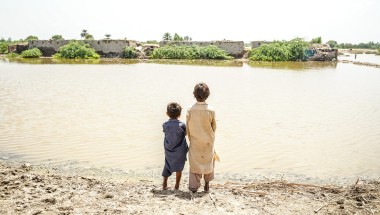 Children look across the floodwaters in Sindh province, Pakistan, where millions of people need urgent help. DEC charity Islamic Relief is providing emergency food and temporary shelter as families do all they can to keep safe and survive. Photo: Islamic Relief