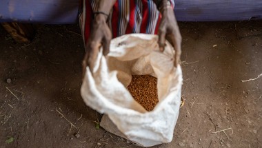 A Kenyan woman holding open a bag of grain