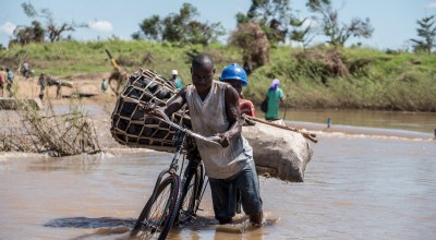Zaccharia Roberto pushes his bicycle laden with charcoal across a flooded river near Nhamatanda, Mozambique. Cyclone Idai has disrupted infrastructure across the country, impacting livelihoods and hampering aid efforts. Photo: Tommy Trenchard / Concern Worldwide