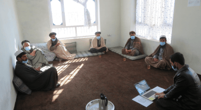 Men sit socially distanced in a meeting room